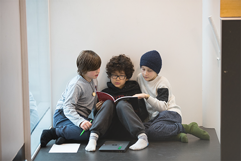 Tre grundskoleelever læser bog